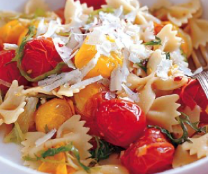 Farfalle con rizada marchita y tomates de la explosión.